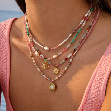 Beaded necklace featured with macaron toned mixed natural chip stones and pearls, matched with a retro embossed sun pendant, ideal for vacation wear.